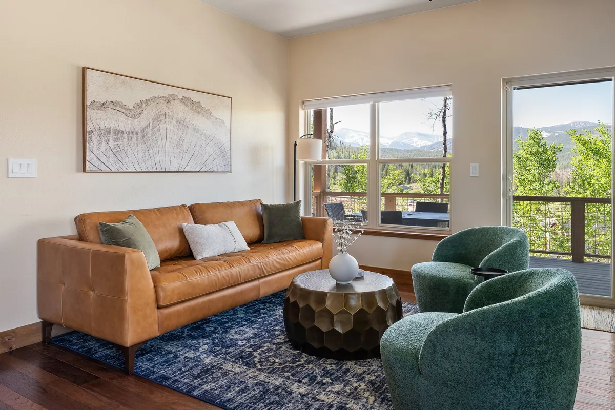A comfortable living space with a leather sofa, geometric coffee table, and large windows framing a breathtaking landscape. The arrangement invites relaxation and conversation, with the view remaining a central feature.