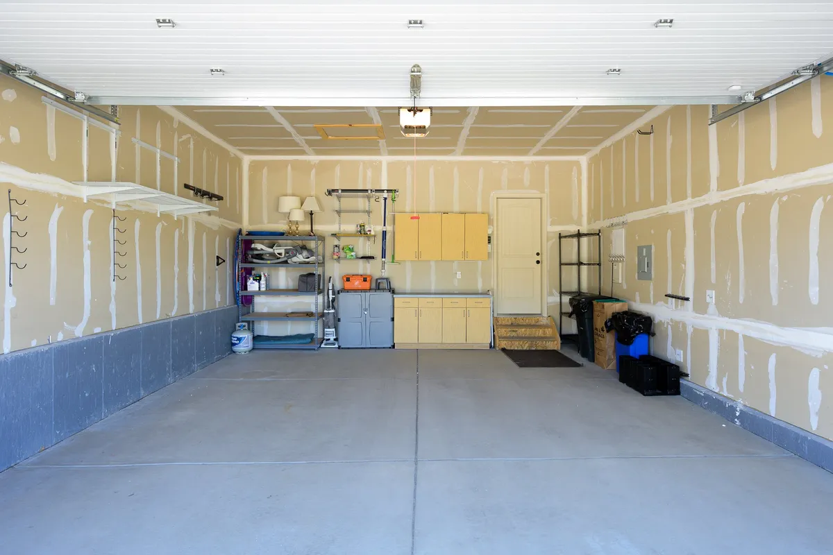 A spacious, orderly garage featuring a workbench, storage shelves, and visible garage door. The environment is clean and practical, perfect for organizing sports equipment or prepping gear for outdoor adventures.